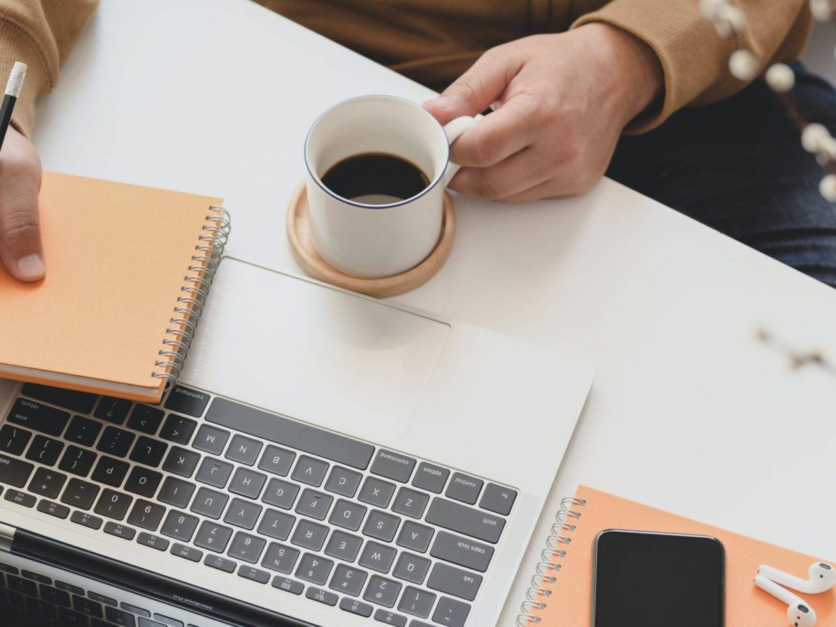 person-holding-white-ceramic-mug-beside-macbook-pro-3787300